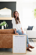 Woman holding a personalized dry-erase calendar in a living room.