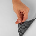 A hand peeling perforated window film that is white on the front and black on the back.