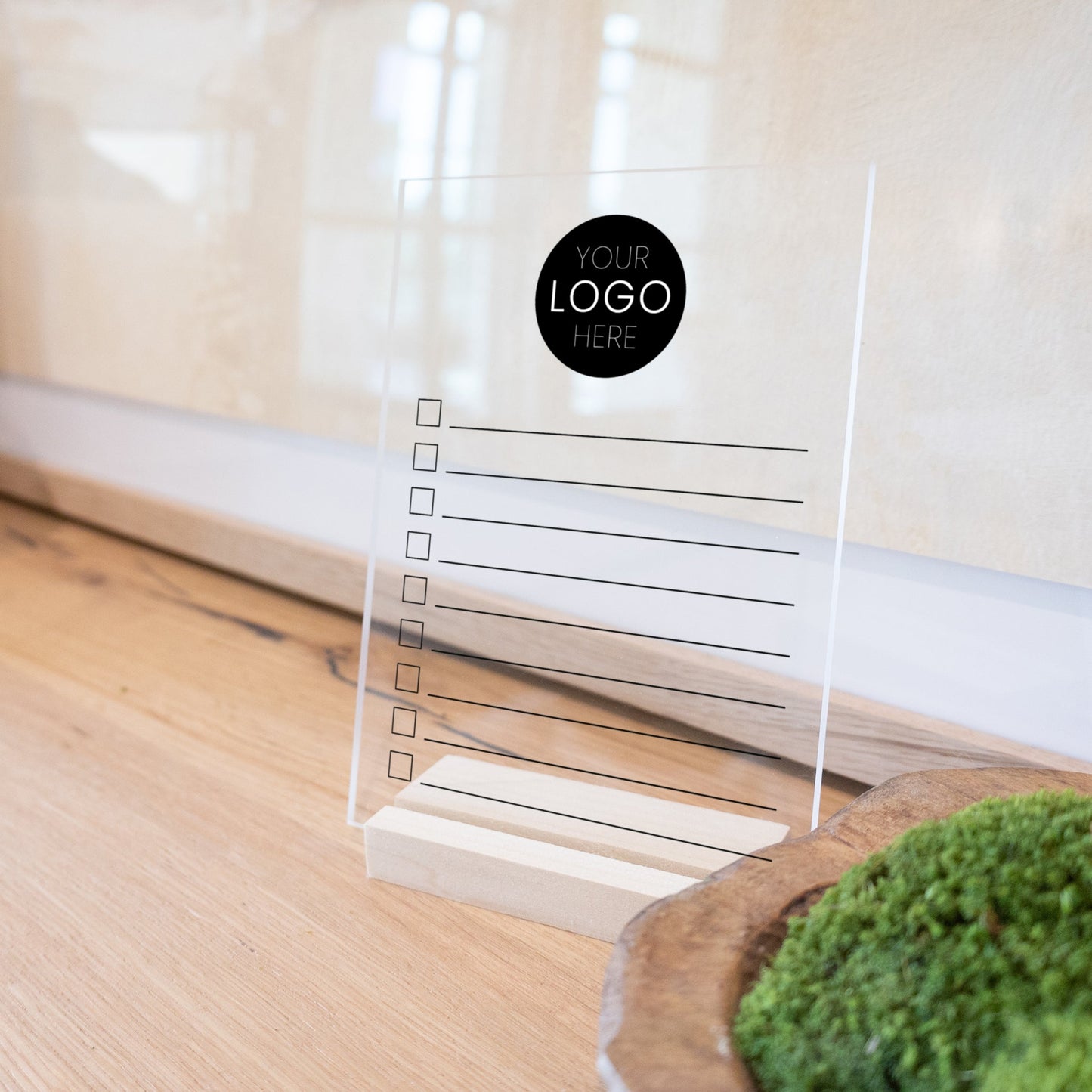 A minimalist to do list printed on clear acrylic with a wooden stand.