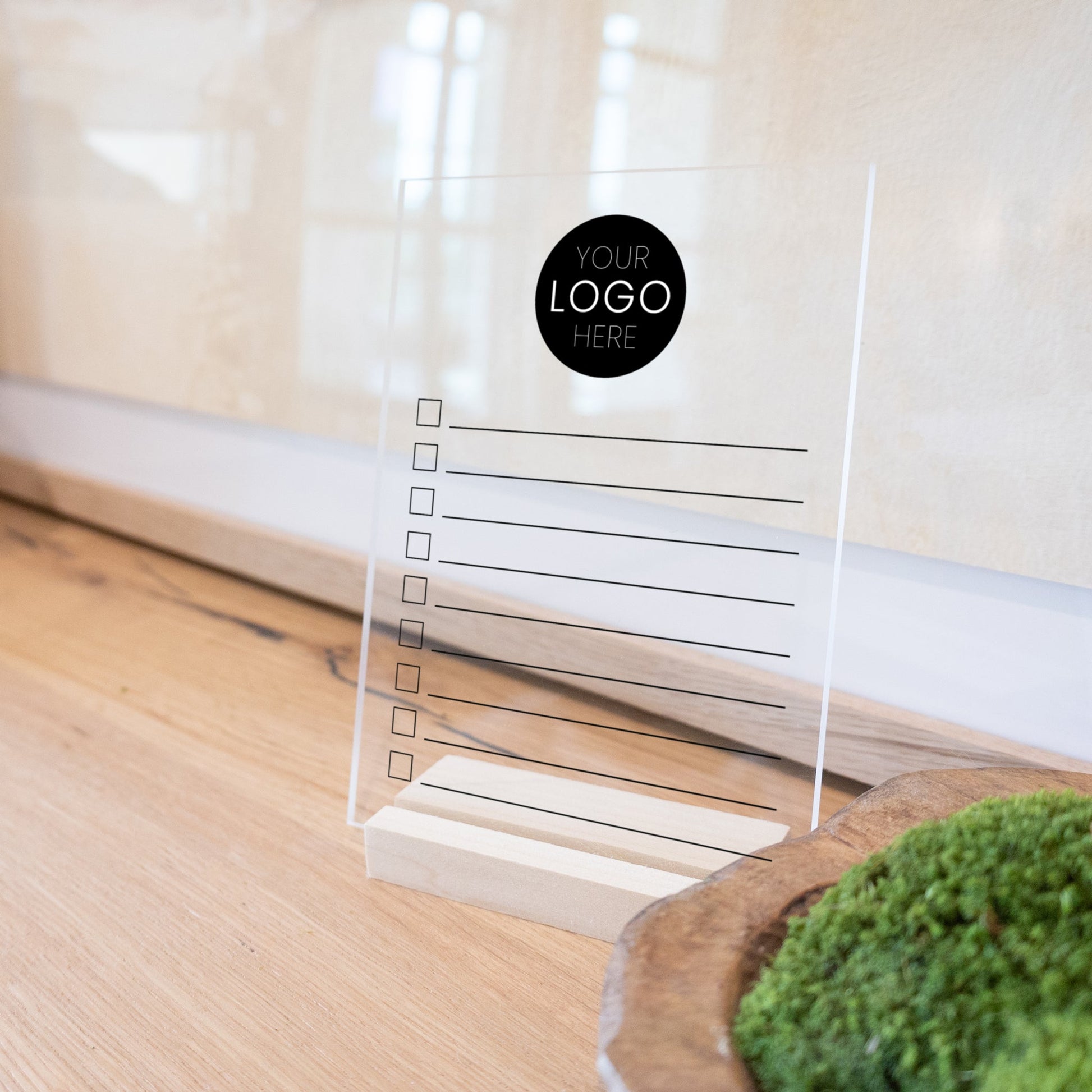 A minimalist to do list printed on clear acrylic with a wooden stand.